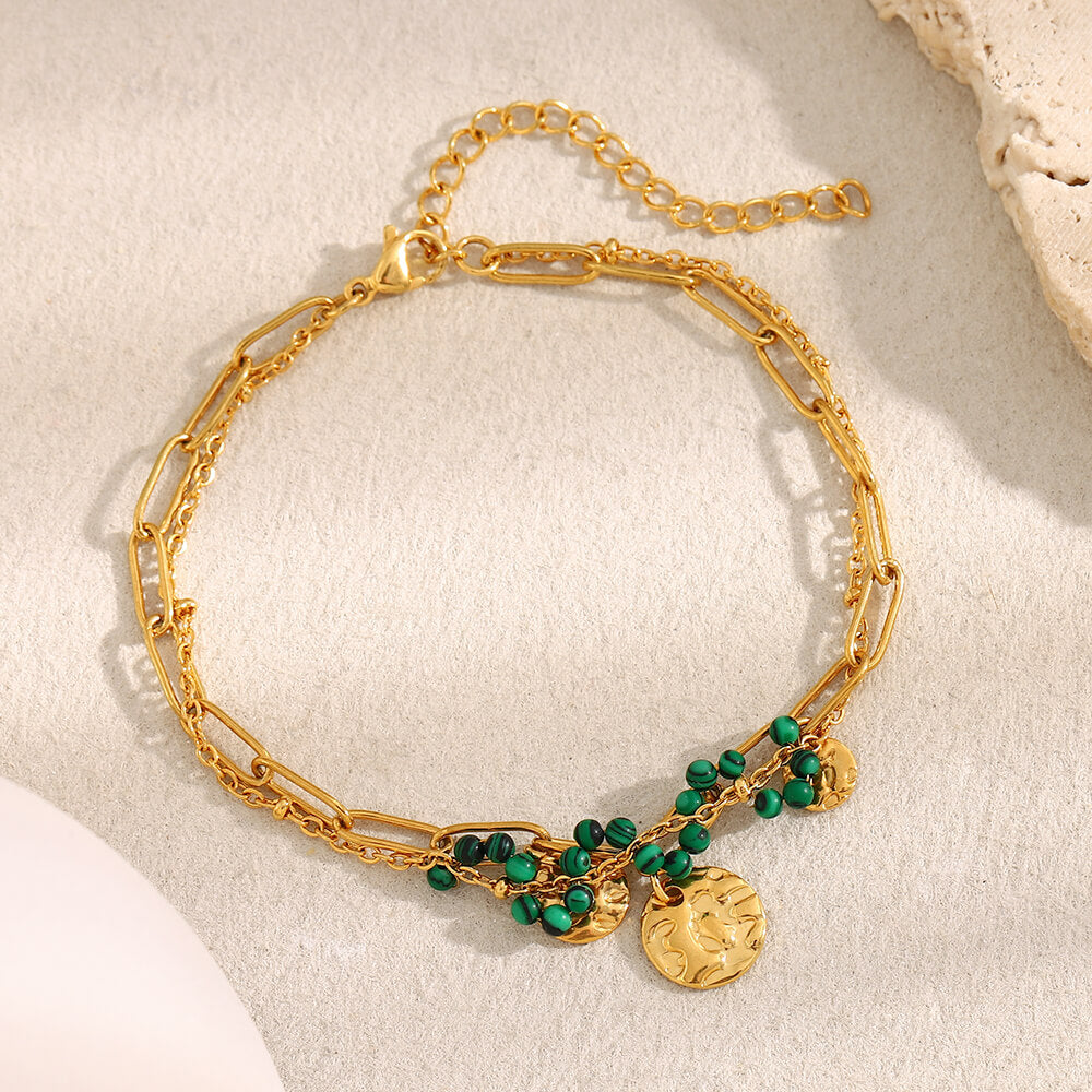 Gold and green beaded bracelet on beige background.