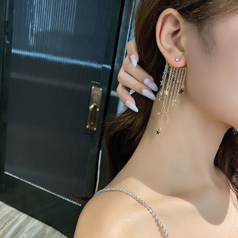 A woman wearing the Gold Star Tassel Statement Earrings.
