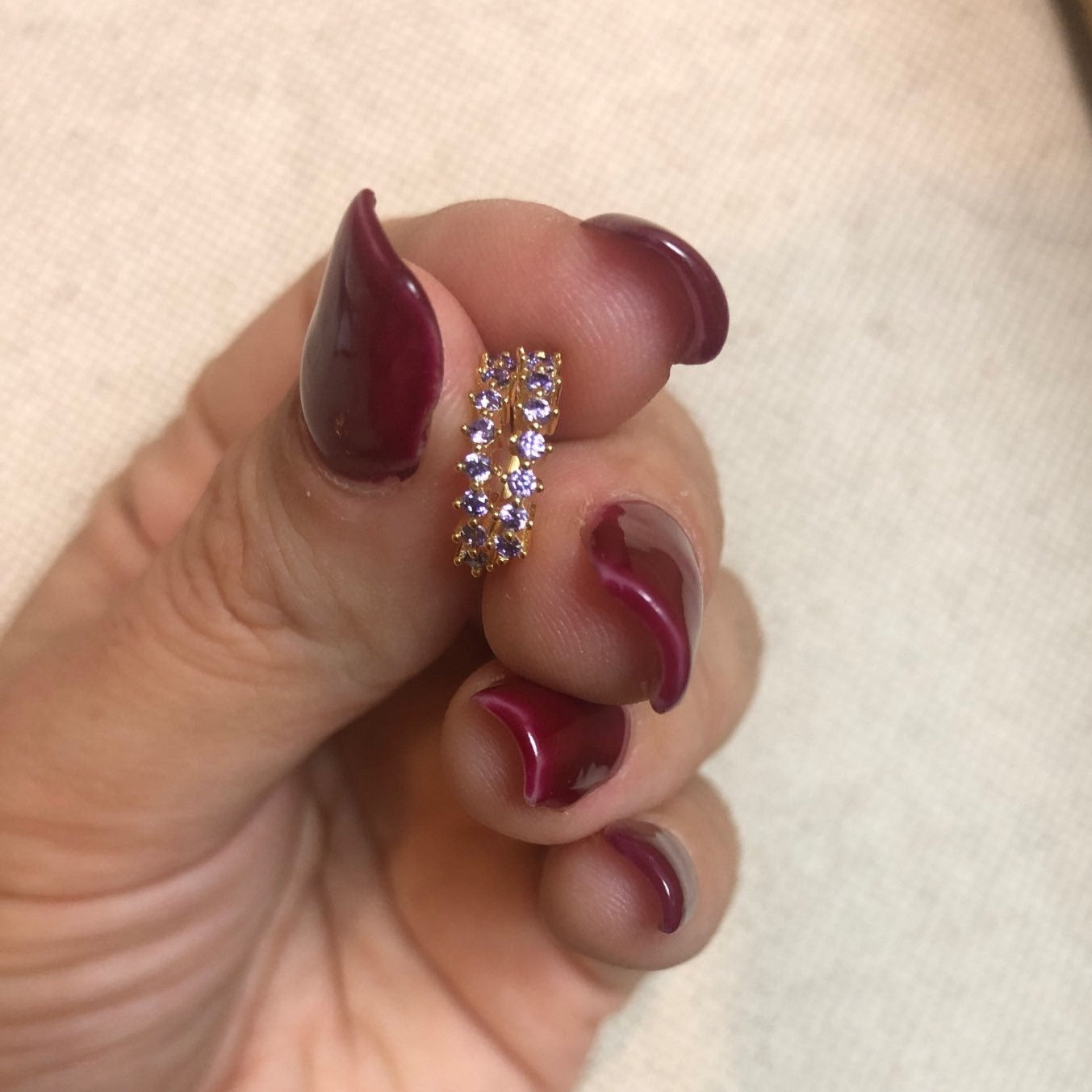 A woman holding a pair of Lilac CZ Huggies.