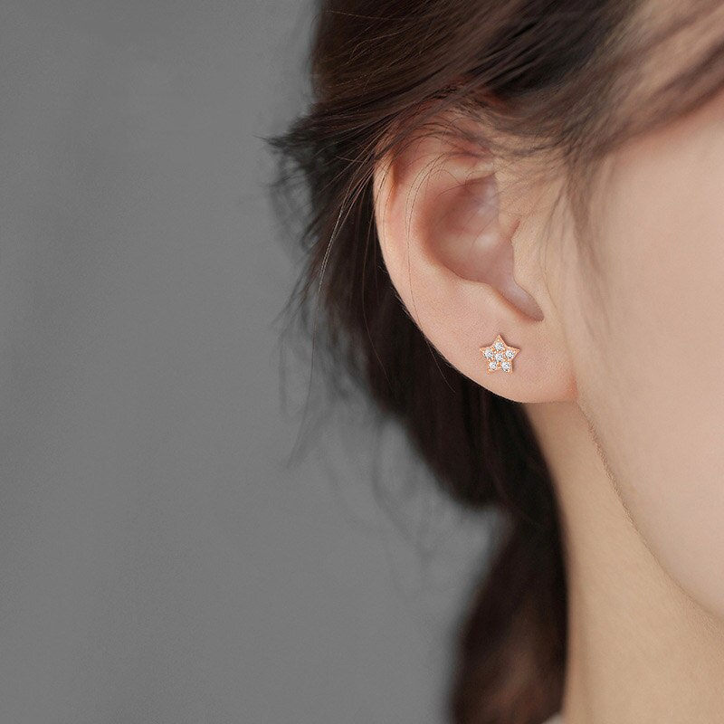 A woman wearing the Teeny Star Studs.