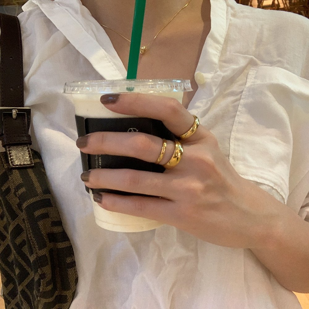 A woman wearing thick gold rings.