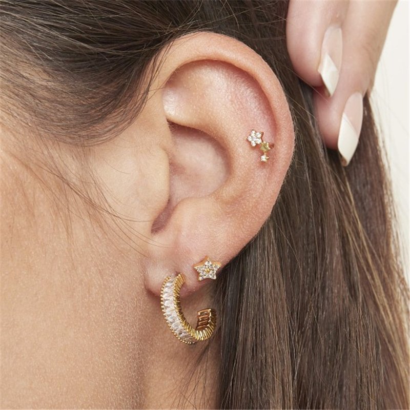 A woman wearing gold CZ star earrings.